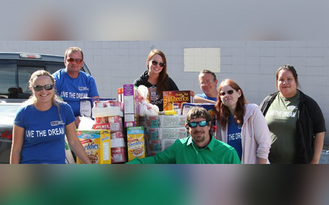 Volunteers gathered outdoors with donated food items.